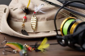 Fishing tackle - fishing spinning rod, hooks and lures on wooden background. Active hobby recreation concept.