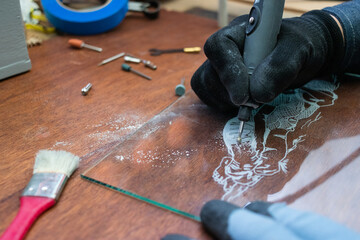 A craftsman does glass engraving with a rotary tool
