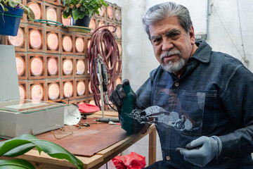 A senior craftsman shows a finished piece of glass engraving