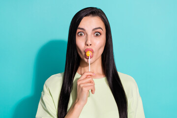Fototapeta premium Portrait of cute lovely lady lick bright tasty candy impressed unbelievable flavor isolated over cyan color background