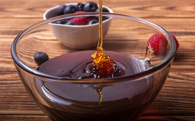 Honey pouring with some berries on the background