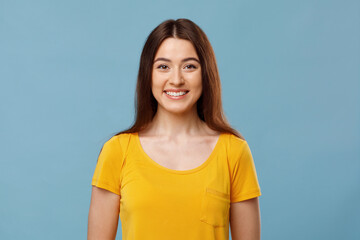 Joyful pretty young lady smiling on blue background