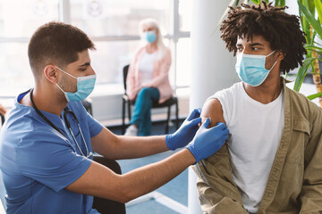 Black Guy Getting Vaccinated Against Covid-19, Doctor Applying Sticking Plaster