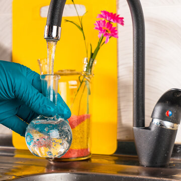 water purification specialist tap water pours into a glass flask.