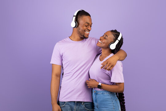 Portrait of black couple in headphones hugging at studio - Powered by Adobe
