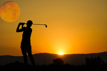 Golfers' hit golf ball toward the hole at sunset silhouetted