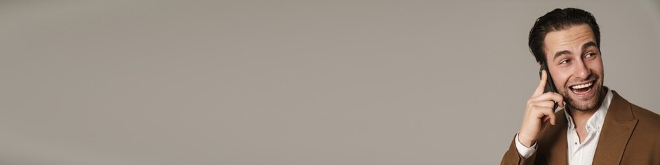 Unshaven excited man laughing and talking on cellphone