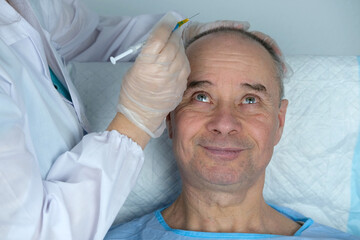 close-up trichologist treats patient, bald mature man with alopecia in hair growth clinic, anti-aging treatments for balding men. concept of hair transplant procedures for men, selective focus