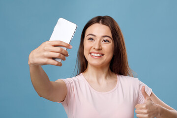 Smiling fair-haired young woman taking selfie on smartphone, closeup
