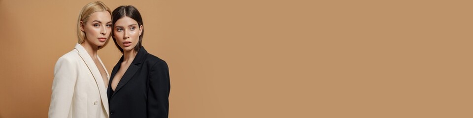 Two beautiful elegant women wearing smart jackets posing