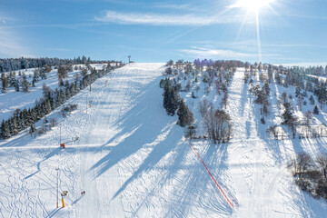 Aerial photo shows an inviting slope for skiing. The sun is shining and the slope is almost...