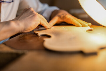 Luthier making a handmade classic italian violin, working  and carving  the f-hole and the top...