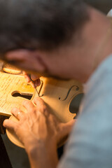 Luthier making a handmade classic italian violin, working  and carving  the f-hole and the top...