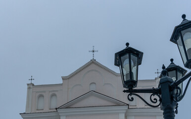Fototapeta na wymiar The upper part of the street lights in the old style on the background of the dome of the Catholic church.