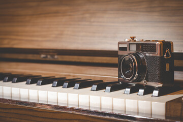 retro camera on classical acoustic piano keys. audio and visual in the past concept