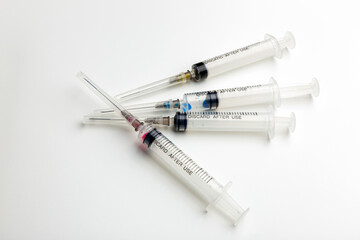Used syringes with a protective cap on the needle with colored injection