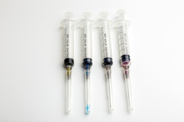 Used syringes with a protective cap on the needle with colored injection