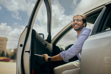 Positive young middle-eastern man going out the car