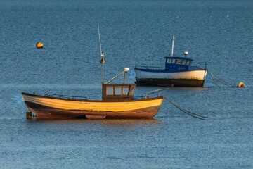 Moored boat illuminated by the rays of the setting sun on the shoal during low tide