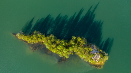 a small summer island on a lake with shadows view from the top