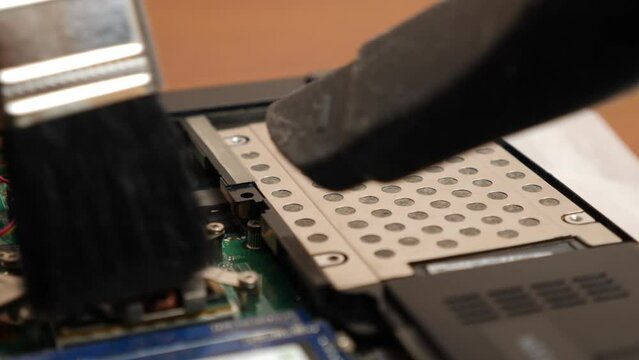 The wizard cleans the laptop's cooling system with a brush and a vacuum cleaner. PC care and repair concept.