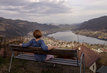 Fototapeta premium A woman sits on a bench on the shore of the lake