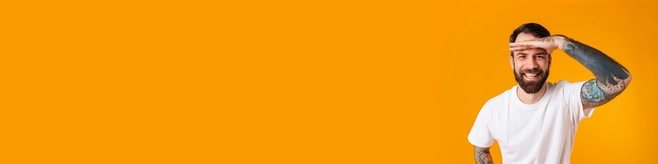 Smiling brunette bearded man looking far straight standing