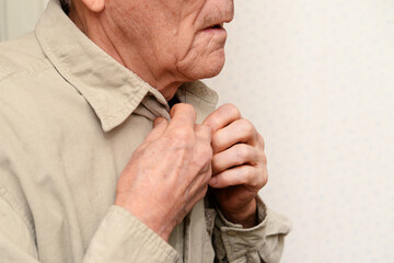 elderly man fastens the collar of shirt