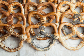 Fresh prepared homemade soft pretzels. Different types of baked pretzels with seeds on a black background