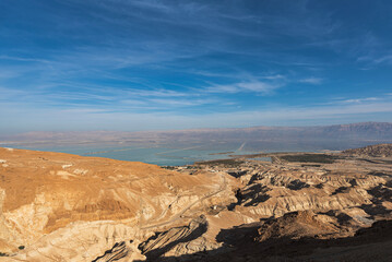Top view of the dead sea with the sandstone hills on the foreground under blue sky.
