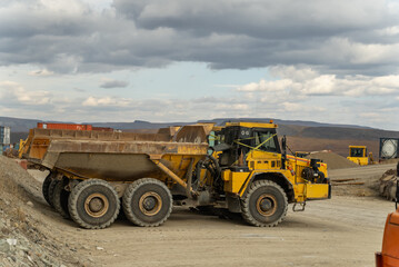 An articulated dump truck waiting to be repaired stands near the containers at the gold mine site.