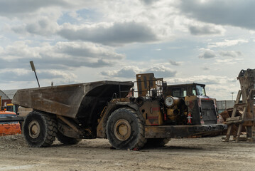 An underground truck stands at a gold mining site near a structure.