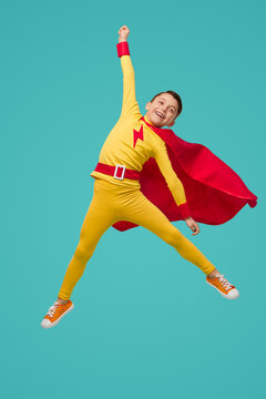 Excited superhero boy jumping and celebrating victory