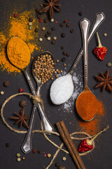 Spices on a black background. Spoons with different spices on a dark surface. traditional spices