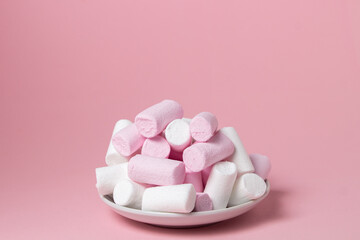 Marshmallows on a pink background. Colored marshmallows on a white plate. Delicate dessert