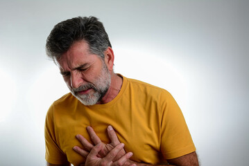 Man with chest pain suffering from heart attack in front off grey background