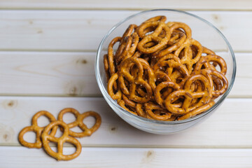 Salted mini pretzels in a deep glass bowl on a wooden tabletop. Popular beer snack. - obrazy, fototapety, plakaty