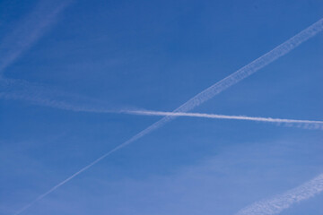 Chmury kondensacyjne po przelocie samolotu na błękitnym niebie. - obrazy, fototapety, plakaty