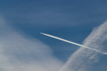 Samolot lecący na błękitnym niebie, pozostawiając za sobą białą smugę kondensacyjną.