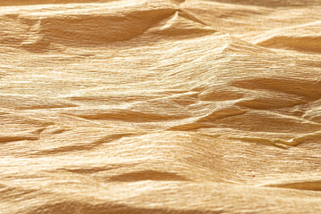 Texture of crumpled paper corrugated beige gold color closeup