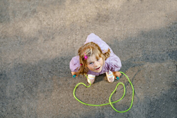 Little preschool girl jump and train with skipping rope. View from above on cute happy active...