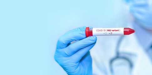 Doctor holding a test blood sample tube positive with IHU variant or strain COVID-19.Copy space