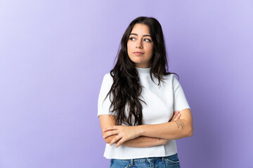 Young caucasian woman isolated on purple background looking to the side