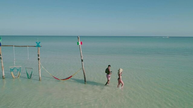 Couple walk in shallow Caribbean water on holiday, Holbox Hammocks