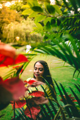 An Indian girl surrounded by a variety of plants at a park.