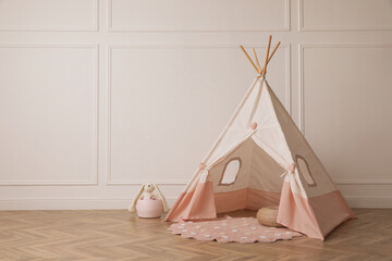 Cute child room interior with play tent near white wall, space for text