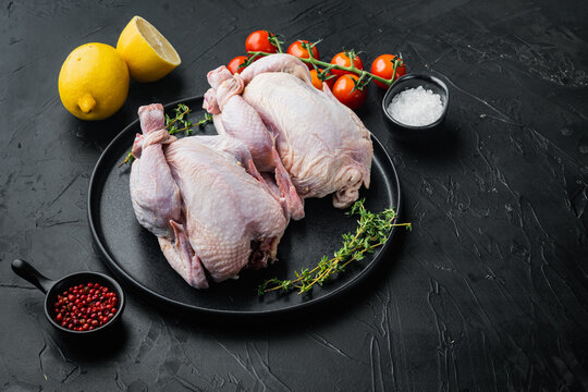 Fresh whole chicken carcass with herbs spices ingredients, on black background