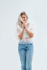 Beautiful blonde in jeans in the studio on a light background.