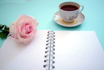 Horizontal background with a rose, a cup of tea and a notebook