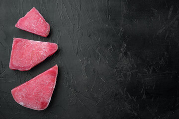 Raw frozen tuna fish fillet, on black stone background, top view flat lay , with copyspace  and...